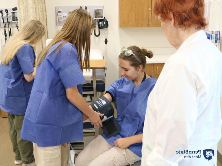 MedCamp 2024 participants checking vitals while Nursing professor observes.